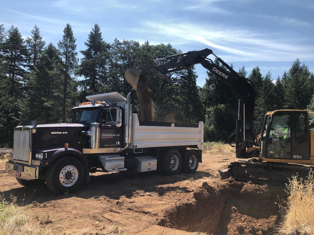 Deere excavator emptying soil into dump truck